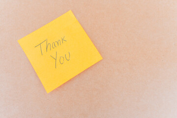 Thank you note that says thank you, handwritten with blue pen on a solid background
