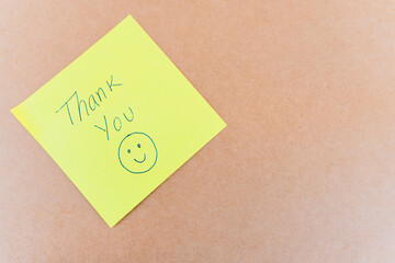 Thank you note that says thank you, handwritten with blue pen on a solid background