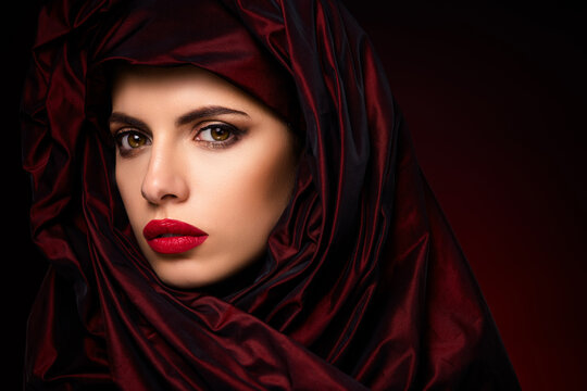 Magnificent portrait of a young woman wrapped in a dark red silk fabric with striking makeup
