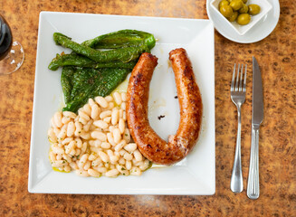 Fried butifarra with baked green bell pepper and portion of white bean stew. Dish is complemented...