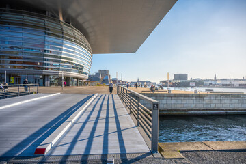 Visitors enjoy a bright sunny day at Copenhagen Opera House, taking in the stunning architecture...