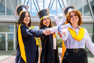 Happy graduates showing diplomas celebrating graduation day