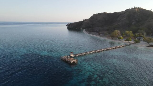 Aerial landscape view of Kanawa Island beach with long bridge dock surrounded by turquoise ocean.