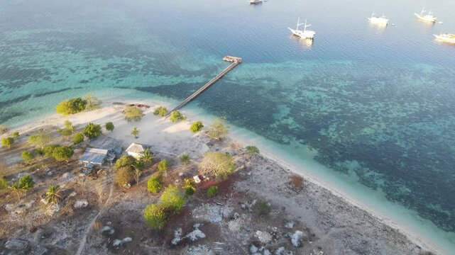 Aerial landscape view of Kanawa Island beach with long bridge dock surrounded by turquoise ocean.
