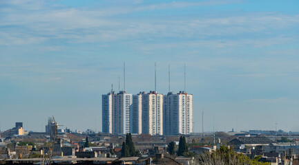 Group of high-rise residential buildings with antenna towers rising above an urban cityscape