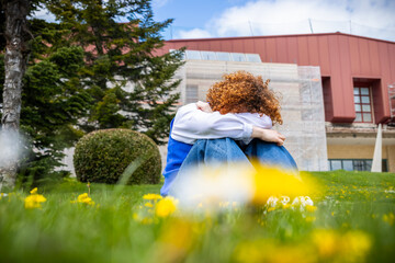 Sad university student feeling depressed on campus lawn