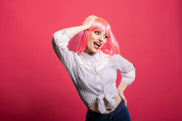 Young female model with pink hair playfully posing against isolated background. Cheerful stylish...