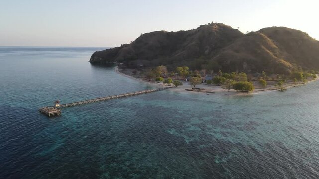 Aerial landscape view of Kanawa Island beach with long bridge dock surrounded by turquoise ocean.