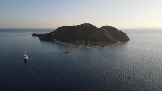 Aerial landscape view of Kanawa Island beach with long bridge dock surrounded by turquoise ocean.