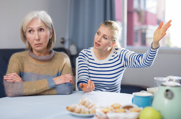Adult daughter quarrels with her mature mother, trying to explain something to her