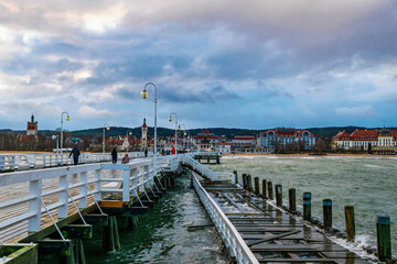 Beautiful old wooden pier in Sopot and stormy sea waves	