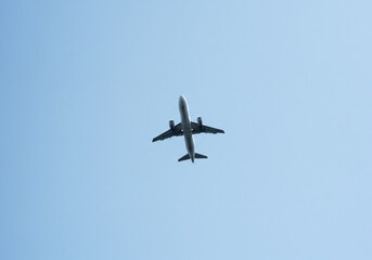 Obraz premium An airplane flies in the sky with its wings spread out against a clear blue background during the day created with generated ai