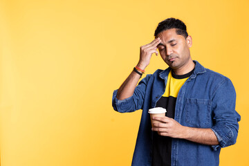 Sleepy man yawning and rubbing eyes sipping coffee to wake up and gain energy. Exhausted person...