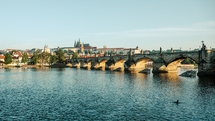 Morning light illuminates Prague Castle and Charles Bridge reflected in the Vltava River,...
