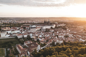 Golden sunlight bathes Prague Castle and the surrounding city at dawn. The vibrant rooftops glow as...