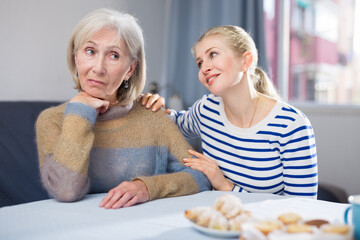Adult daughter is trying to comfort her mature mother, who is upset about something