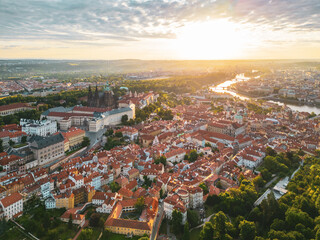 Golden sunlight bathes Prague Castle and its surroundings at dawn, casting long shadows across the...