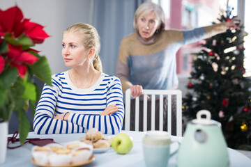 Mature woman scolds her adult daughter, who came to visit her before Christmas, pointing out her...