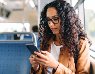 Young woman deletes social media apps on smartphone with focused expression while sitting in a bus during a quiet afternoon