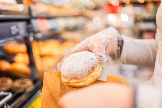 Girl Is Putting Donut In Bag At Supermarket - Powered by Adobe