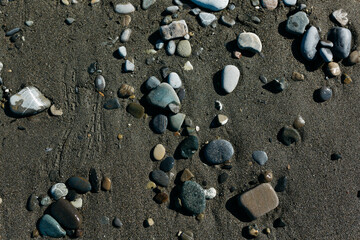 glossy stones washed by the sea wave shine from the rays of the sun on a summer day. pebbles on the city beach.the concept of environmental protection from pollution by petroleum products and plastics