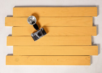 A vintage camera and flash are set on neatly arranged wooden boards, showcasing a minimalist...