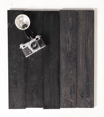 A vintage camera rests on a black wooden surface, accompanied by a studio light, ideal for artistic...