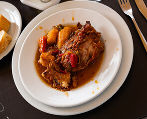 Segovian pork legs - stewed in sauce with onions and carrots, with addition of spicy seasonings. Dish garnished with potato