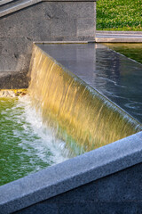 Waterfall in the park with a cascade of artificial decorative ponds framed by stone and granite...