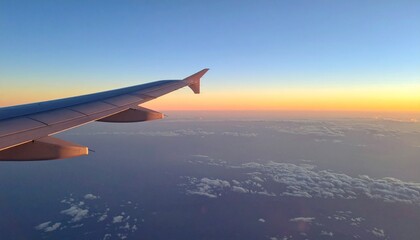 Obraz premium Airplane wing soars above the clouds at a stunning golden hour sunrise, capturing a beautiful travel moment.