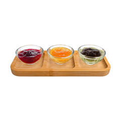 Three round clear glass bowls with assorted jams on a wooden tray, ideal for gourmet breakfasts, buffet displays, and modern food photography
