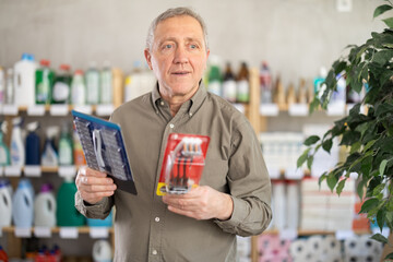 When choosing razor set, mature man gets acquainted with new product. Client compares products from...