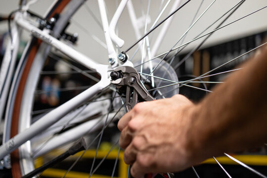 Close up view of serviceman screwing the bolt of bicycle rear wheel. Bike maintenance and workshop.