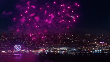 Aerial footage shows fireworks over San Francisco Bay at sunset on July 4th, with colorful explosions lighting up the skyline and vibrant reflections dancing on the water during Independence Day. - Powered by Adobe