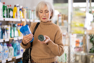 Elderly female shopper buying plastic garbage bags in supermarket