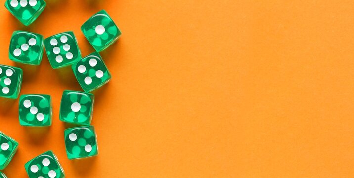Green dices on orange background with space for text, top view
