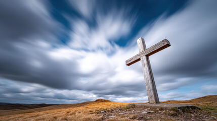 Weathered wooden cross stands tall on windswept hill under dramatic cloudy sky, evoking solitude and spirituality in remote natural landscape
