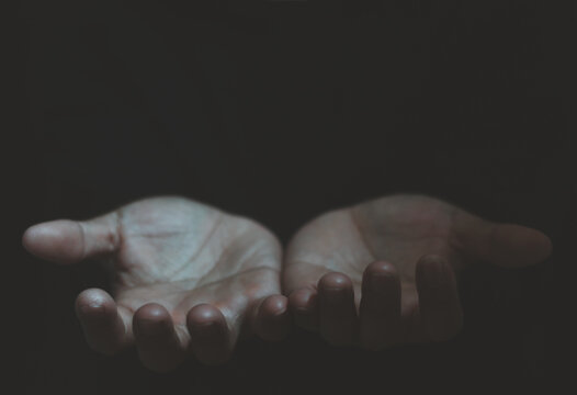 Person open palm hand concept. Open hands in darkness symbolizing hope, giving, receiving, help, charity, sharing, hope, prayer, support, kindness, faith, and human emotion with copy space for text.