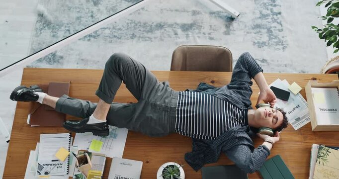 Above, headphones and relax with business man in office for streaming, song charts and sound. Music, radio performance and audio subscription with person and podcast in media agency for record label