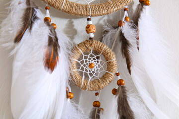 Dream catcher hanging on light wall, closeup