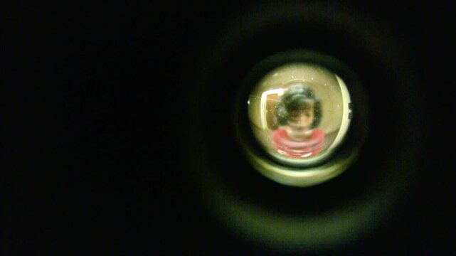 Looking through peephole at woman in hotel hallway