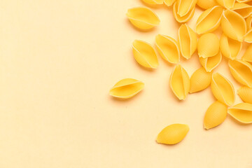Heap of raw conchiglie pasta on yellow background