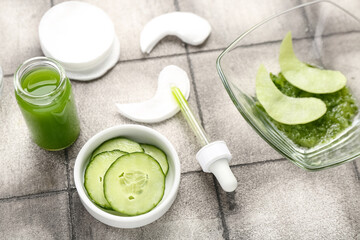 Cotton under-eye patches with cucumber slices on grey tile background
