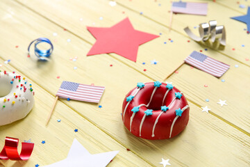 Composition with donuts, USA flags and confetti on yellow wooden table. Independence Day celebration