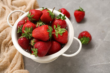 Colander with fresh strawberries on grey background