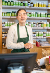 Woman seller happily invites to buy dietary supplements and vitamins in an eco supermarket....