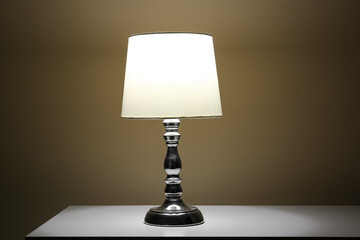 Glowing lamp on white table in dark room