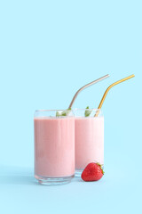 Glasses of tasty strawberry smoothie on blue background