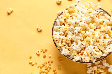 Bowl with tasty popcorn on yellow background