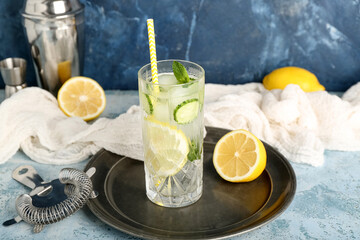 Glass of mojito with cucumber on grunge light blue table